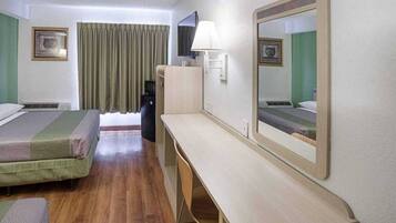 A hotel room with two beds, a desk, a chair, a television, and a mirror.