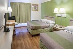Ein Hotelzimmer mit zwei Betten, einem Schreibtisch mit Computer, einem Stuhl, einem Fernseher und zwei Nachttischlampen.