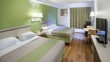 A hotel room with two beds, a desk, a television, and a window with curtains.