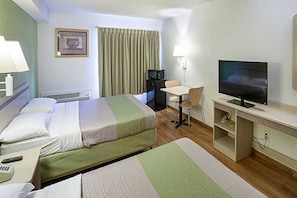 Una habitación de hotel con dos camas, un escritorio, un televisor y una silla.