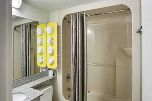 Un baño con ducha, inodoro y lavamanos con espejo.