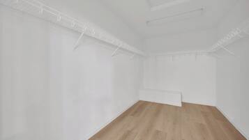 A room with white walls, a wooden floor, and a ceiling with a grid of lights.