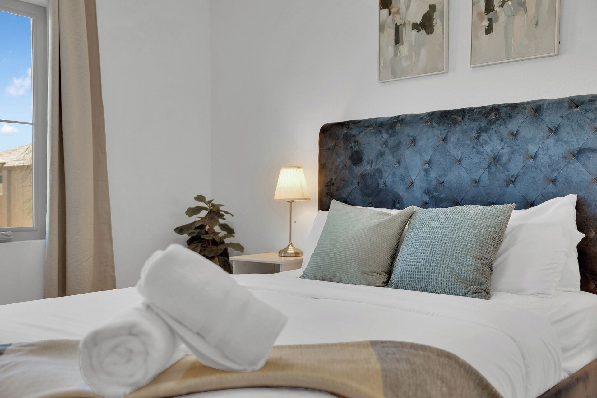 A hotel room with a bed, a nightstand, a lamp, and a plant.