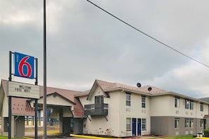 Un motel con un grande cartello che indica il numero 6, un cartello di benvenuto per wi-fi gratuito e un edificio a due piani con tetto piatto.
