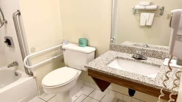 A bathroom with a white toilet, a sink with a granite countertop, and a bathtub.