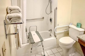 Un baño con bañera, inodoro, ducha y barra de apoyo.