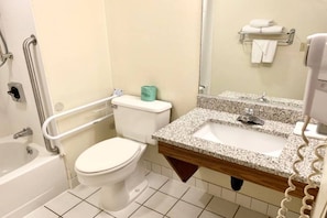 Un bagno con un water bianco, un lavabo con piano in granito e una vasca da bagno.