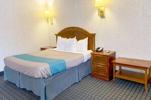 Ein Hotelzimmer mit einem Bett, einem Nachttisch, einer Lampe und einem kleinen Schreibtisch.