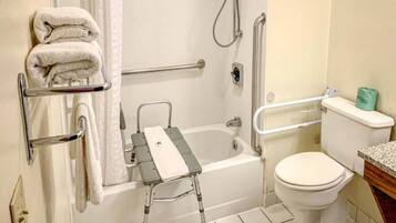A bathroom with a bathtub, a toilet, a shower, and a grab bar.