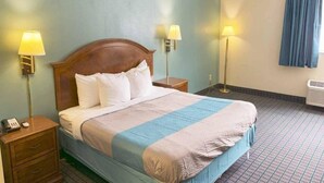 Habitació d'hotel amb llit, dues làmpades de nit, una petita taula de nit, finestra amb cortines i un radiador.