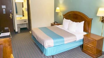 A hotel room with a bed, bedside tables, a nightstand, a mirror, and a bathroom.