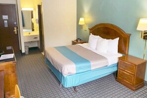 Ein Hotelzimmer mit einem Bett, Nachttischen, einem Spiegel und einem Badezimmer.