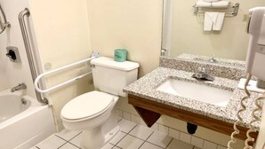 Un bany amb vàter blanc, un lavabo amb taulell de granat i una banyera.