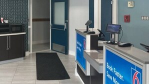 A reception area with a desk, computer, and a sign promoting a book faster service. - Cozy Full Bed Room|Free Parking (East Syracuse)