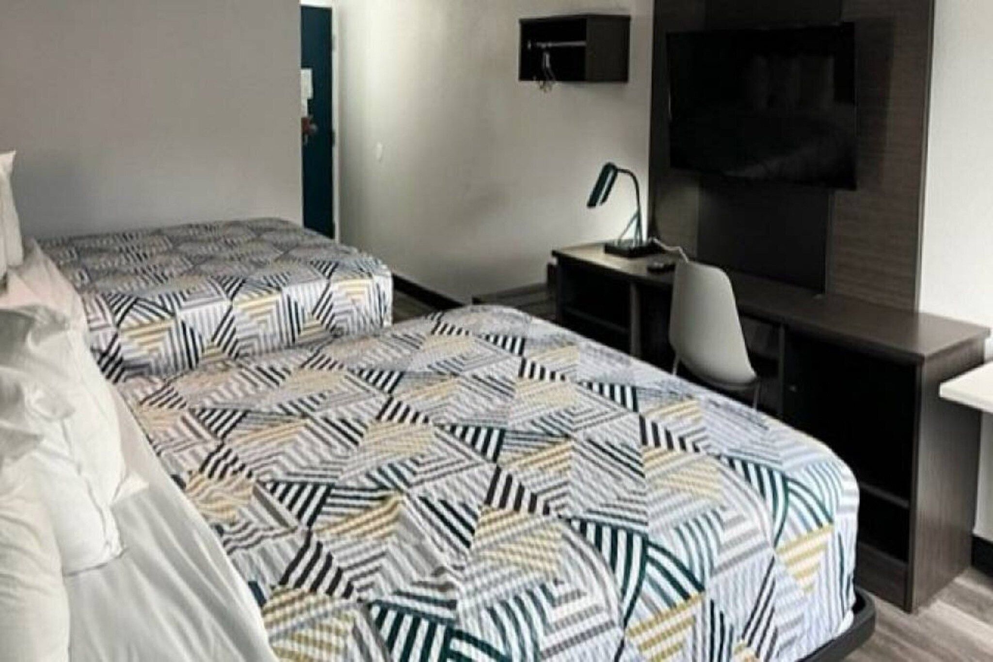 Habitación de hotel con dos camas, un escritorio, una silla, un televisor y una mesita.