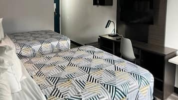 Habitación de hotel con dos camas, un escritorio, una silla, un televisor y una mesita.