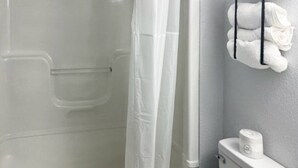 Une salle de bain avec une douche à parois de verre, des toilettes et un porte-serviettes avec des serviettes.