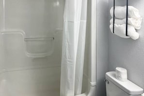Ein Badezimmer mit Duschkabine, Toilette und Handtuchhalter mit Handtüchern.