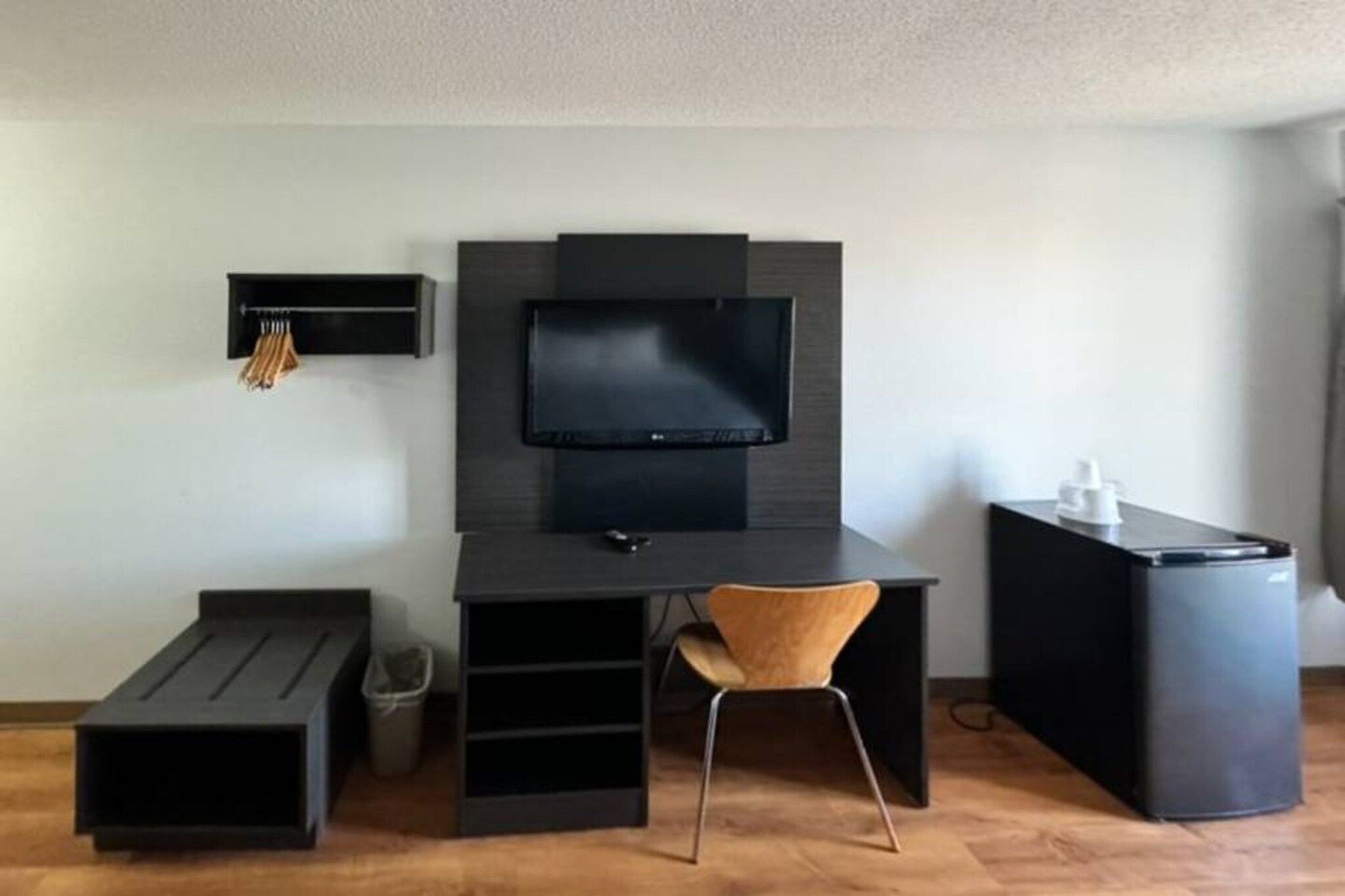 A modern room with a desk, chair, television, and a trash bin.