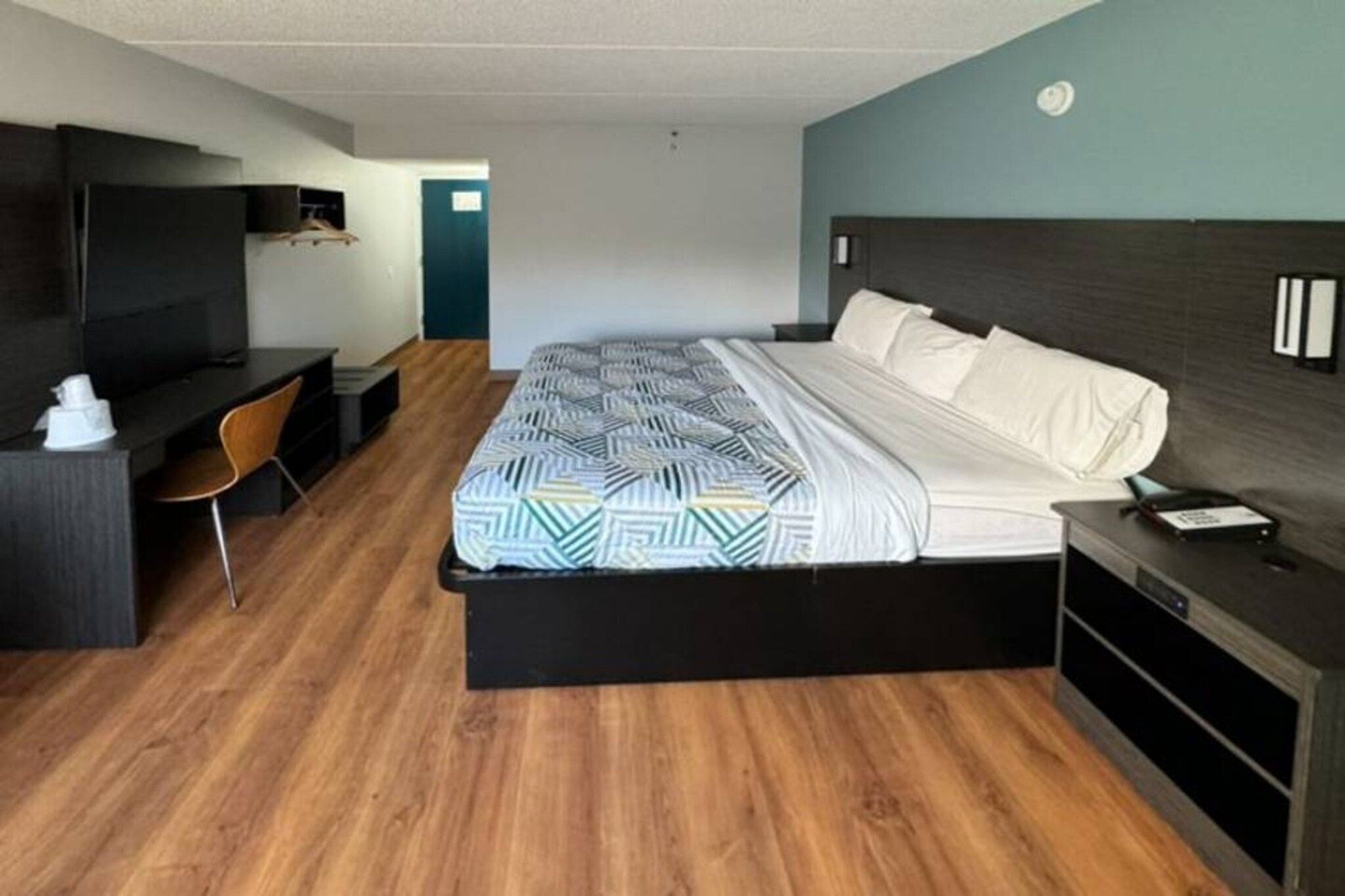 Een hotelkamer met een bed, een bureau, een stoel en een televisie.