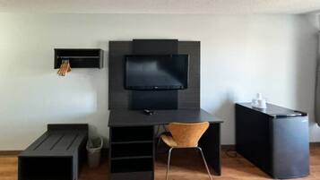 A modern room with a desk, chair, television, and a trash bin.