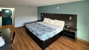 Une chambre d’hôtel avec un lit, une table de chevet, un bureau et une chaise.