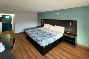 Een hotelkamer met een bed, nachtkastje, bureau en stoel.