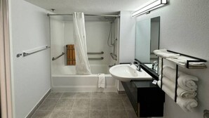 Une salle de bain d’hôtel standard, équipée d’une baignoire, d’un lavabo et d’un miroir.