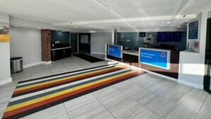 A modern hotel lobby with a striped carpet, a reception desk, and a digital screen displaying a message. - 2 Queen Beds|Mobility|Tub|Nsmk (East Syracuse)