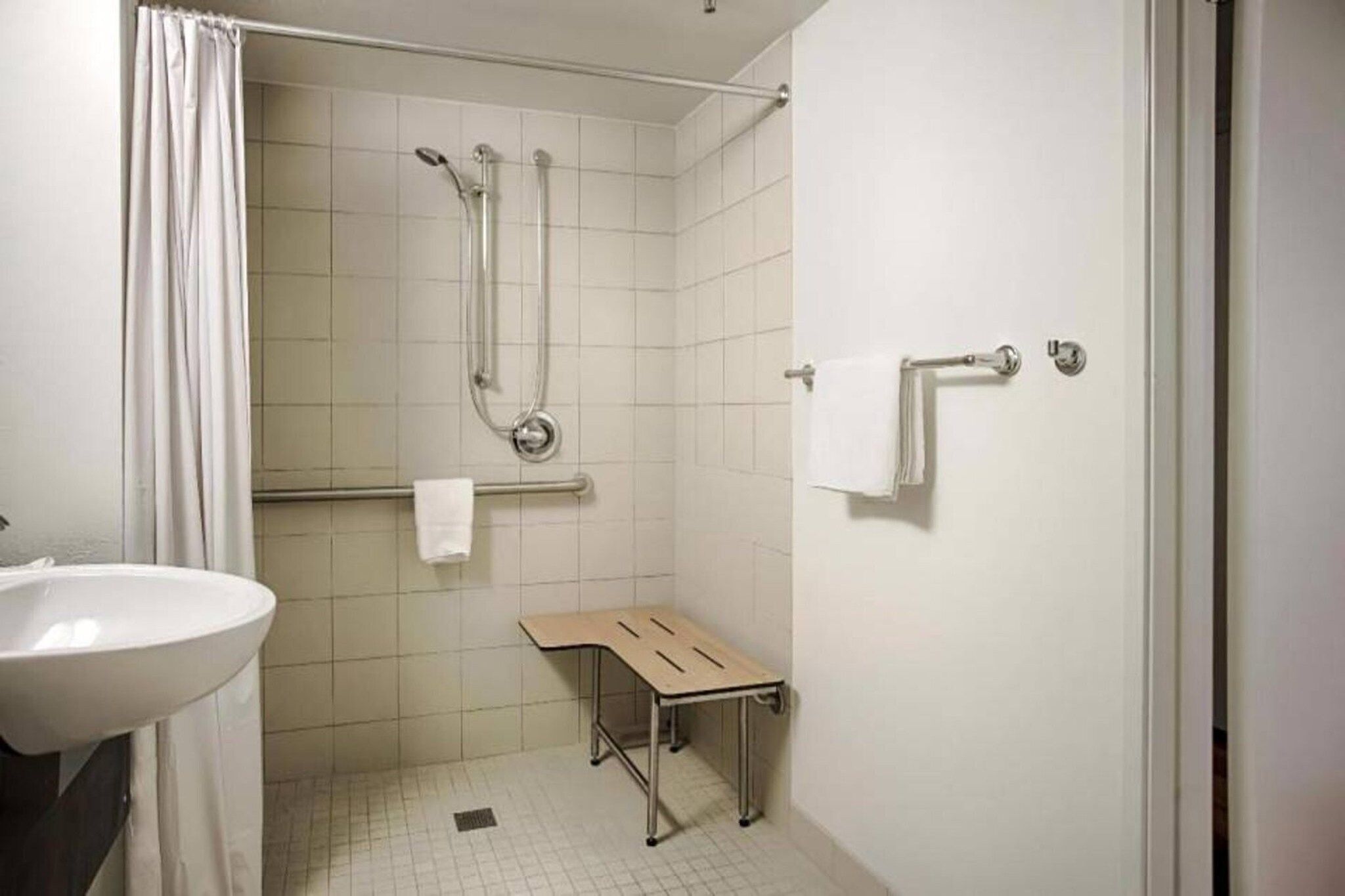 Une salle de bain avec une douche, un lavabo et un banc.