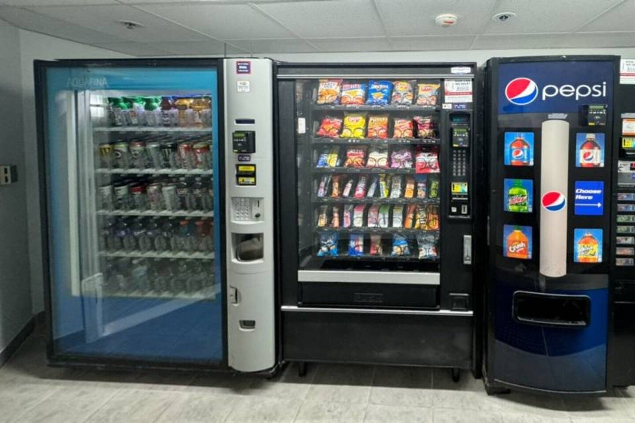 Zona de máquinas expendedoras con una máquina de Pepsi y un dispensador refrigerado de bebidas.