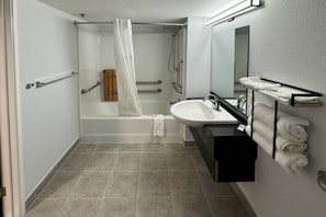 Ein standardmäßiges Badezimmer mit Badewanne, Waschbecken und Spiegel.