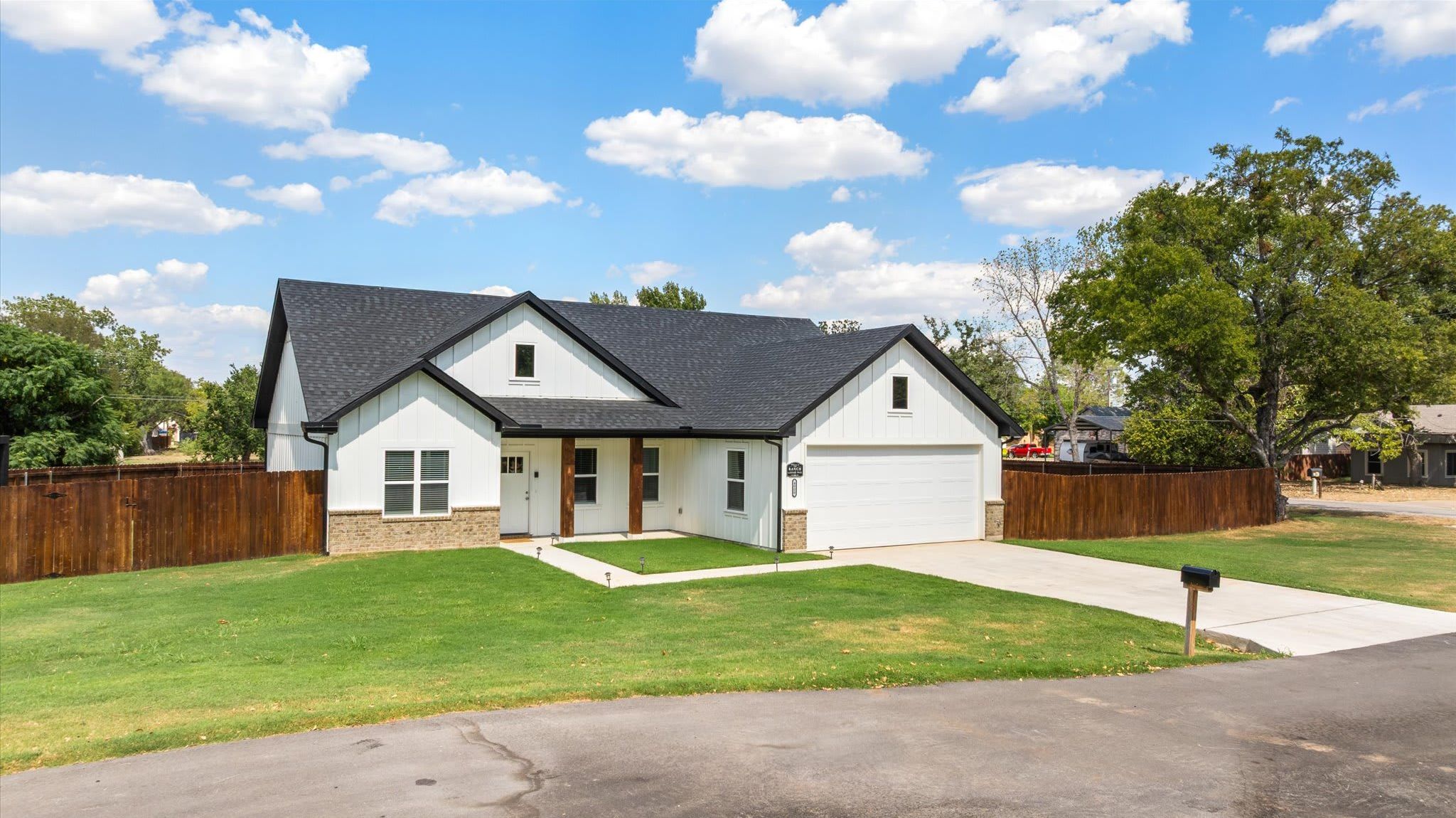 A single-story house with a garage, a front lawn, and a wooden fence.