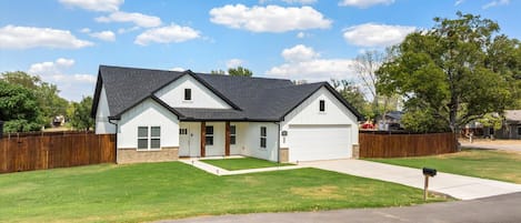 A single-story house with a garage, a front lawn, and a wooden fence.