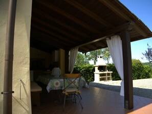 An outdoor patio area with a table and chairs, a covered seating area, and a barbecue grill. - Holiday Home in Palaia With Swimming Pool (Palaia)