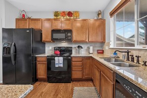 A kitchen with wooden cabinets, a black refrigerator, a stove, a microwave, and a dishwasher.