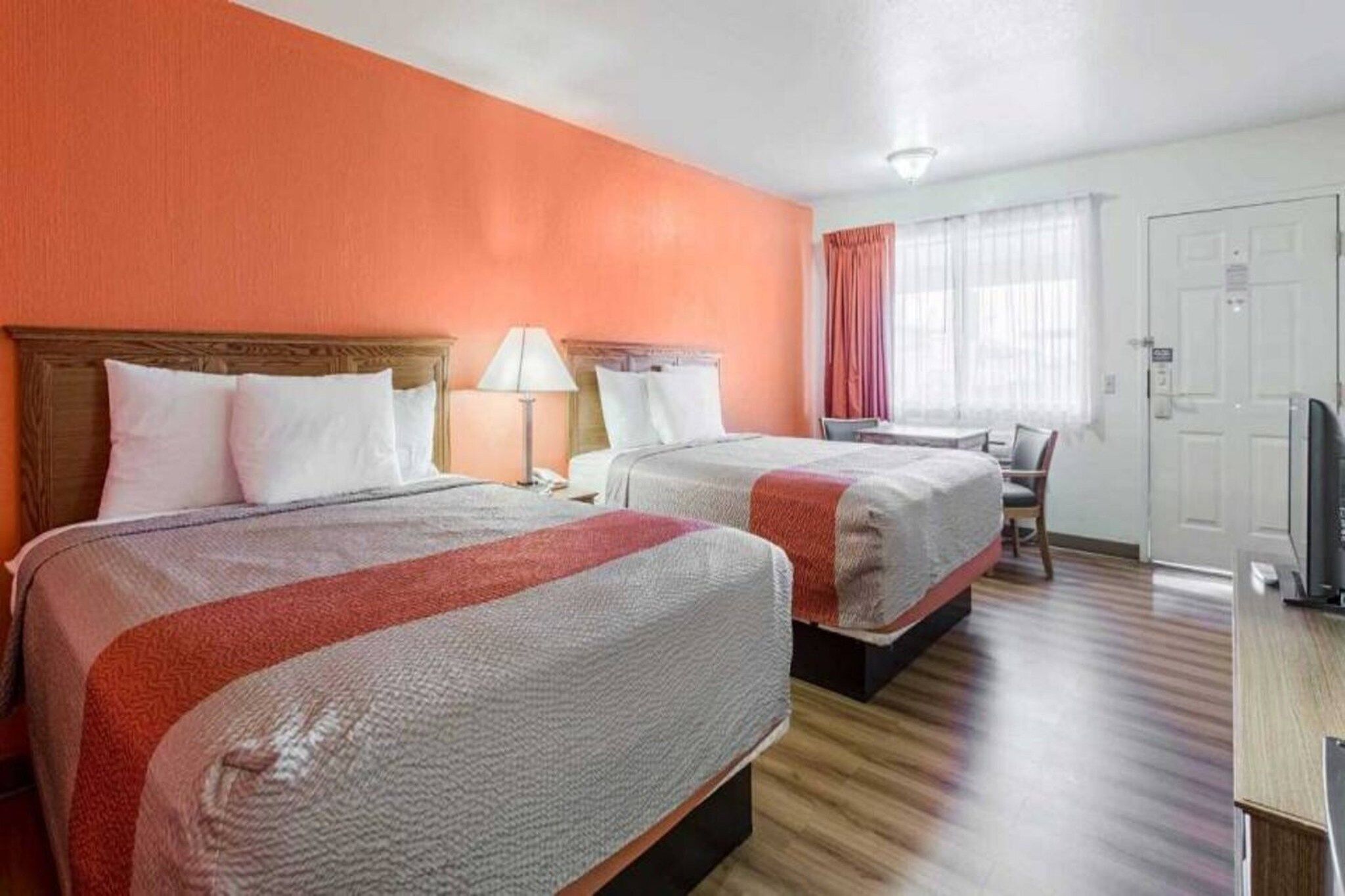 Habitación de hotel con dos camas, un escritorio y una televisión.