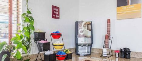 Una cocina de hotel con estación de café, máquina de café y un cartel que indica los horarios de café.