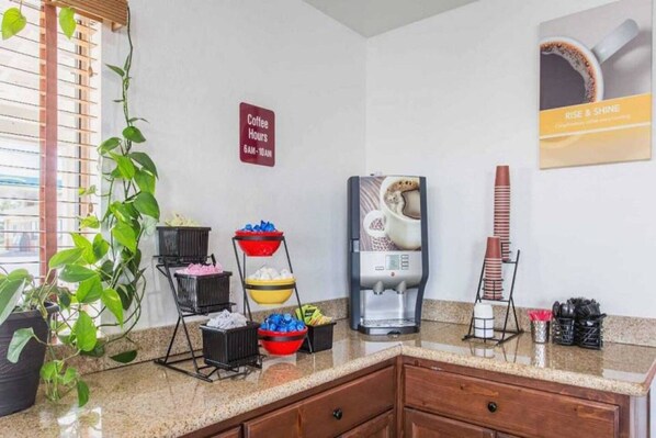 A hotel kitchen with a coffee station, a coffee machine, and a sign indicating coffee hours.