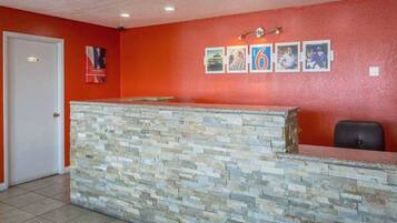 A reception area with a stone counter, a white door, and a red wall with framed pictures.