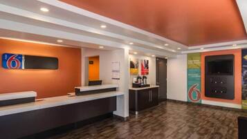 A reception area with a counter, a coffee machine, and a door in the background.
