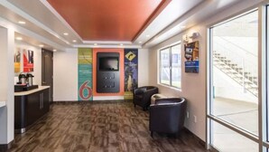 Um lobby moderno com piso de madeira, balcão de recepção, área de estar com cadeiras e escada para um andar superior.