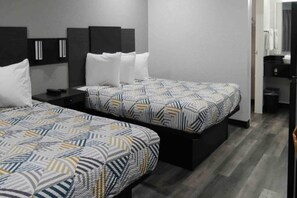 A hotel room with two beds, each with patterned bedding, a bedside table, and a wardrobe. - 2 Queen Beds|NS|Kitchen (Tacoma)