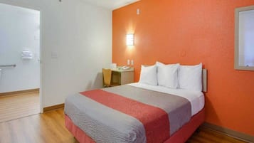 A hotel room with a bed, a desk, and a chair.
