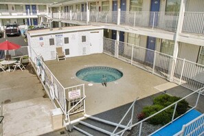 Un hotel con zona de piscina, que incluye un jacuzzi, un cartel que indica acceso para huéspedes y un balcón cercado.