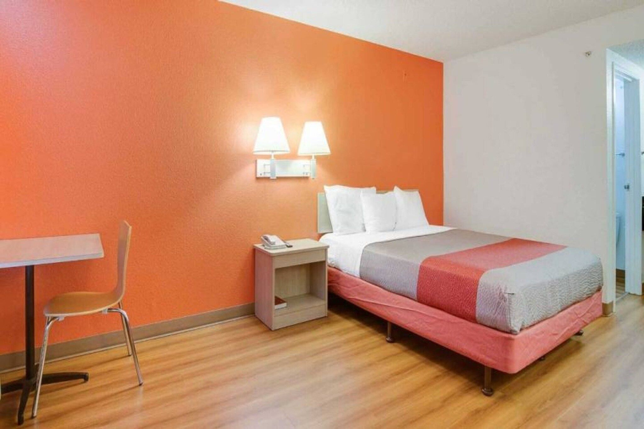 A hotel room with a bed, a nightstand, a chair, and a desk.