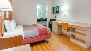 Habitació d'hotel amb un llit, escriptori, cadira i televisió.