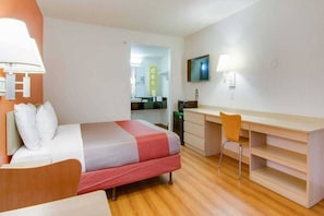 Ein Hotelzimmer mit Bett, Schreibtisch, Sessel und Fernseher.