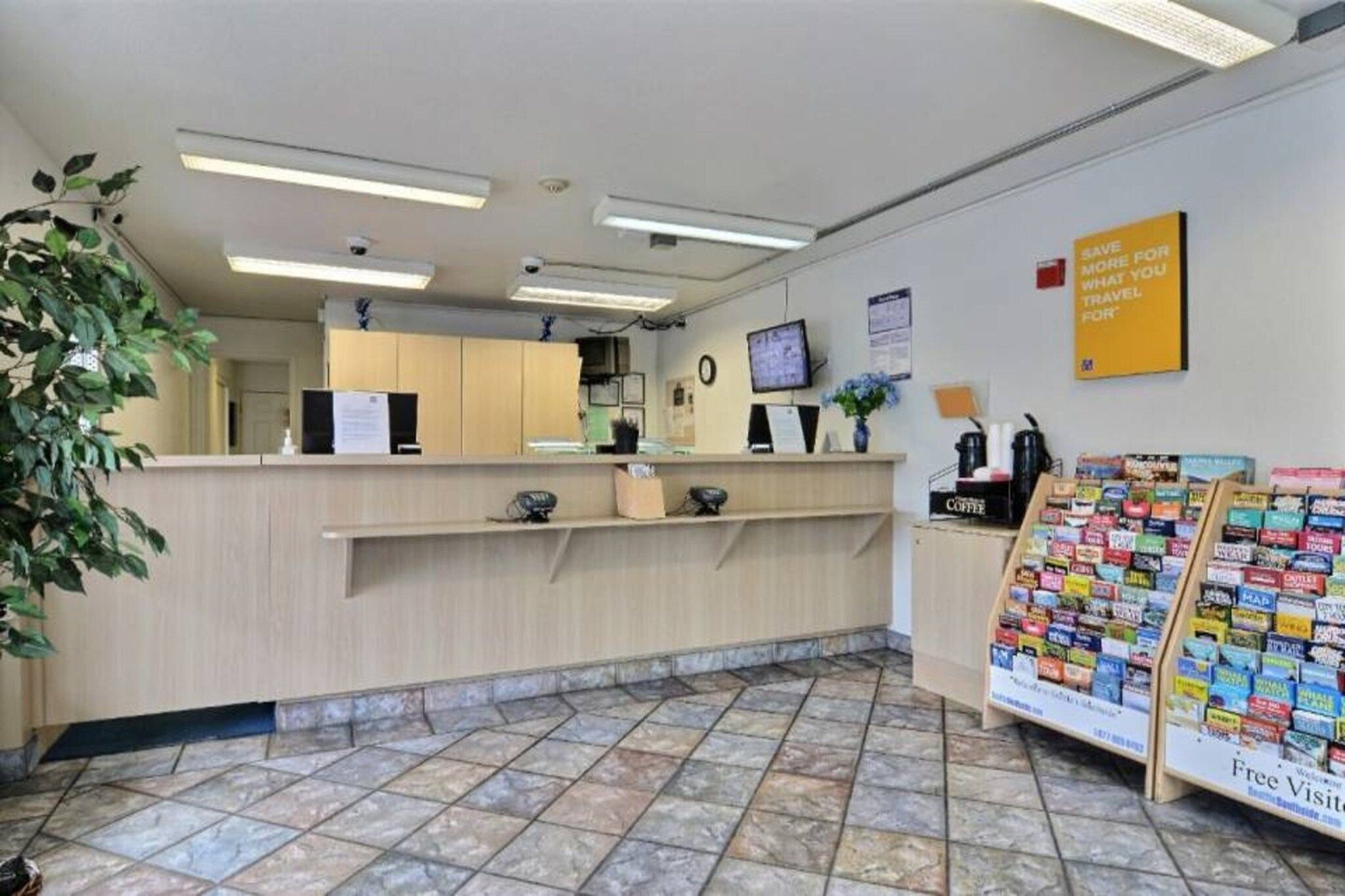 A reception area with a counter, a coffee machine, and a display of travel brochures.