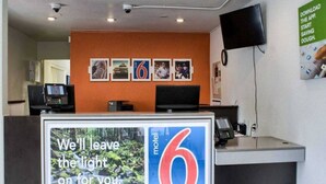 A hotel reception desk with a large sign reading 'We'll leave the light on for you.' - 1 Queen Bed | Micfridge, Non-Smoking (Seattle)